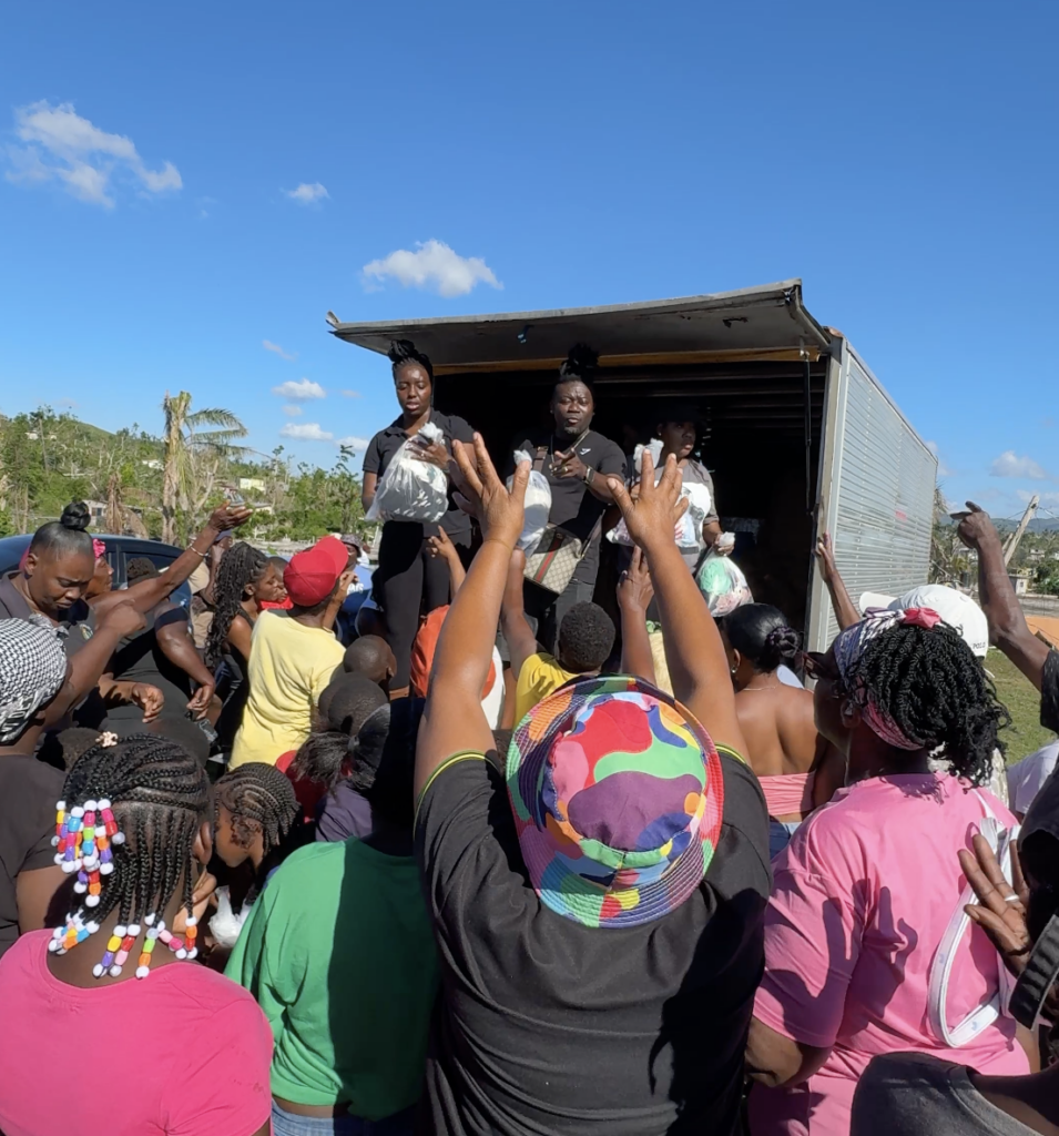 Two people in a truck handing out donation bags to people in Jamaica
